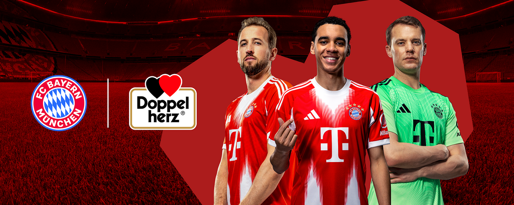 Na zdjęciu trzej zawodnicy FC Bayern Monachium w klubowych strojach: jeden w czerwonym trykocie z numerem, drugi w zielonym stroju bramkarskim, a trzeci uśmiechnięty, wskazujący w stronę obiektywu. W tle znajduje się murawa stadionu i logo klubu.